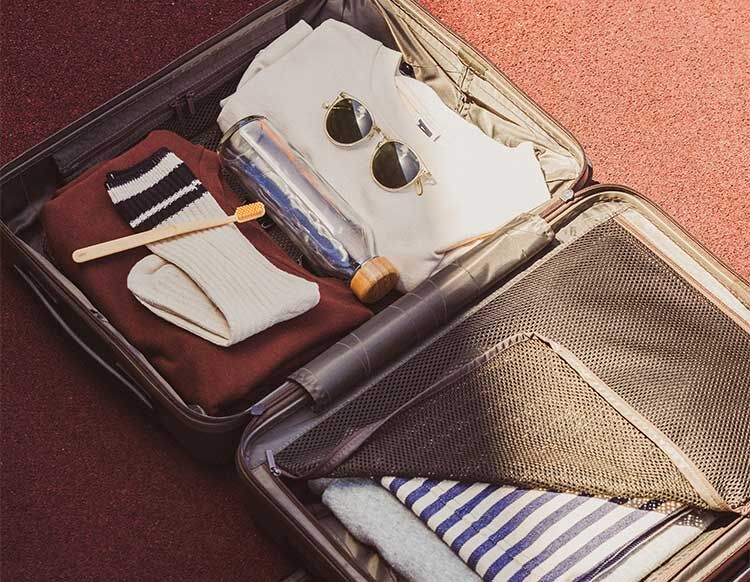 Reisevorbereitung Ein gepackter Koffer mit verschiedenen Urlaubsutensilien